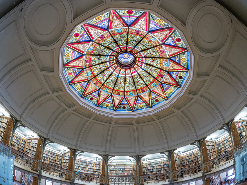 Stained-glass dome ceiling in the Rotunda of Linderman Library at Lehigh University, with bookshelves lining the circular walls below.