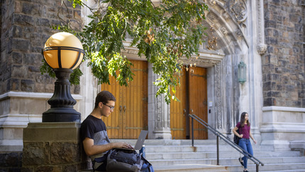 Student using a laptop outside Linderman Library at Lehigh University.