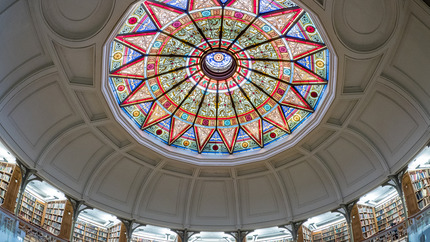 Stained-glass dome ceiling in the Rotunda of Linderman Library at Lehigh University, with bookshelves lining the circular walls below.